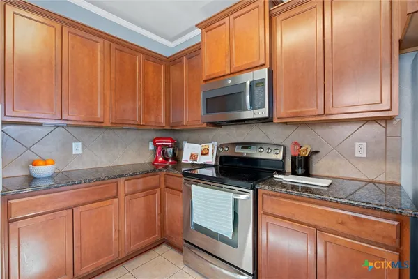a kitchen with stainless steel appliances granite countertop a stove a sink and a microwave