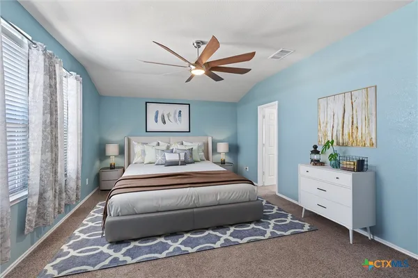 a bedroom with a large bed and a chandelier fan