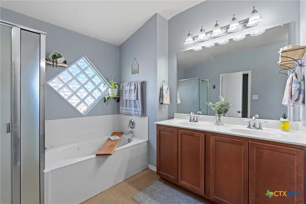 a bathroom with a sink double vanity granite tub and a mirror
