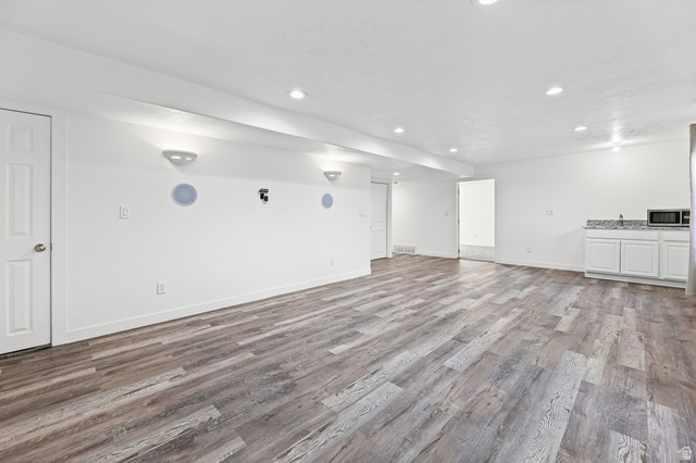 5525 Hampton Way Stansbury Park, UT 84074 - Photo 23 of 35 Expansive open-concept room featuring wood-finish flooring, recessed lighting, and a built-in wet bar with a stone countertop and white cabinetry