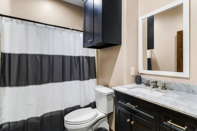 a bathroom with a granite countertop toilet sink and mirror