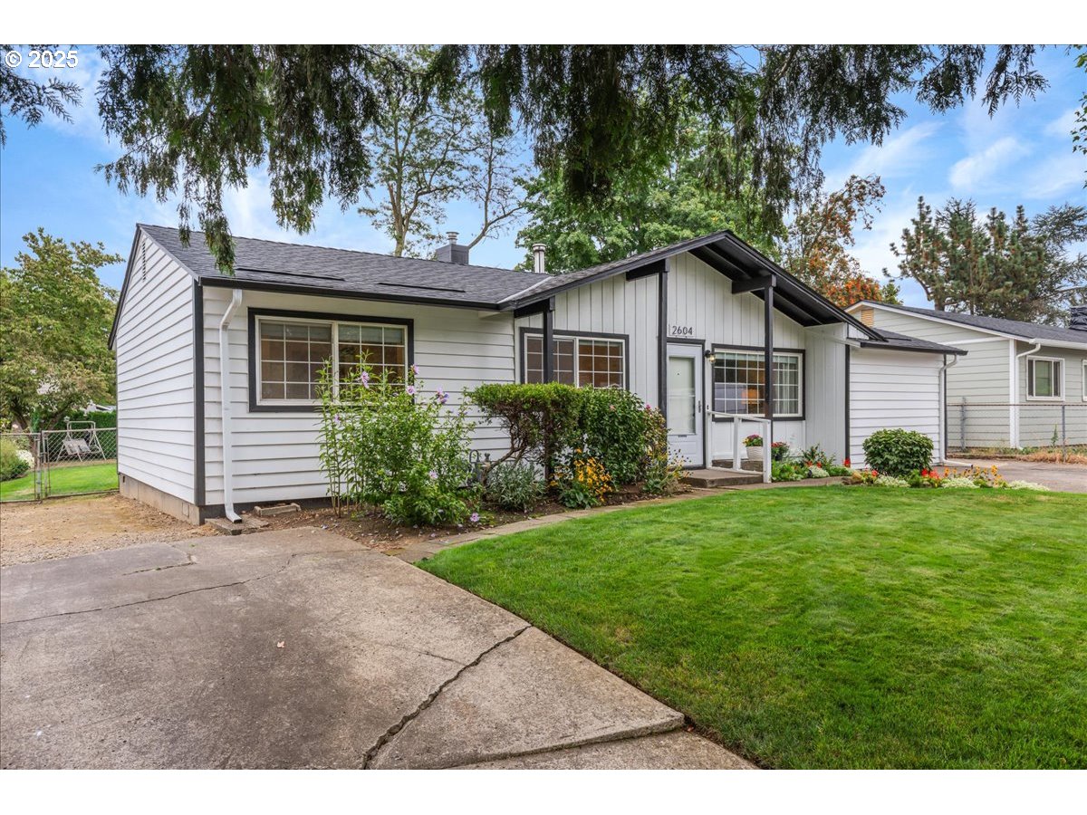 2604 Southeast 176th Place Portland, OR 97236 - Photo 3 of 27 a view of a yard in front of a house with plants and large tree