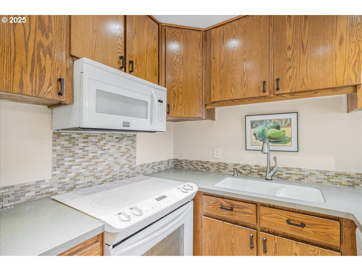 2604 Southeast 176th Place Portland, OR 97236 - Photo 8 of 27 a kitchen with a sink cabinets and a wooden floor