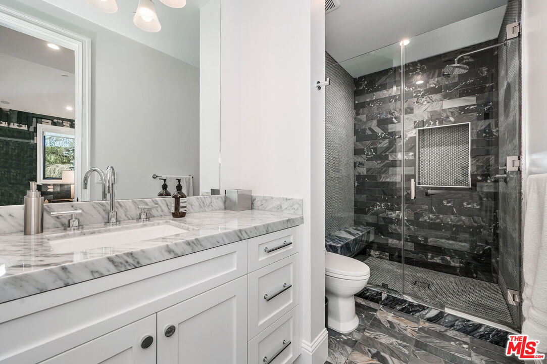 4421 Haskell Avenue Encino, CA 91436 - Photo 25 of 32 a bathroom with a granite countertop sink a toilet a mirror and shower