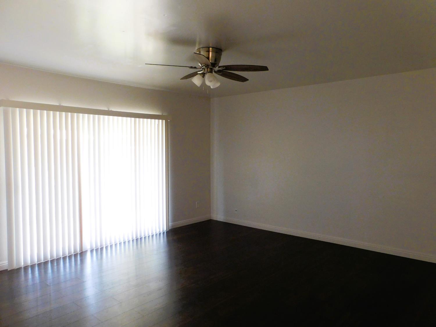 51 West Richert Avenue Clovis, CA 93612 - Photo 4 of 13 an empty room with wooden floor fan and windows