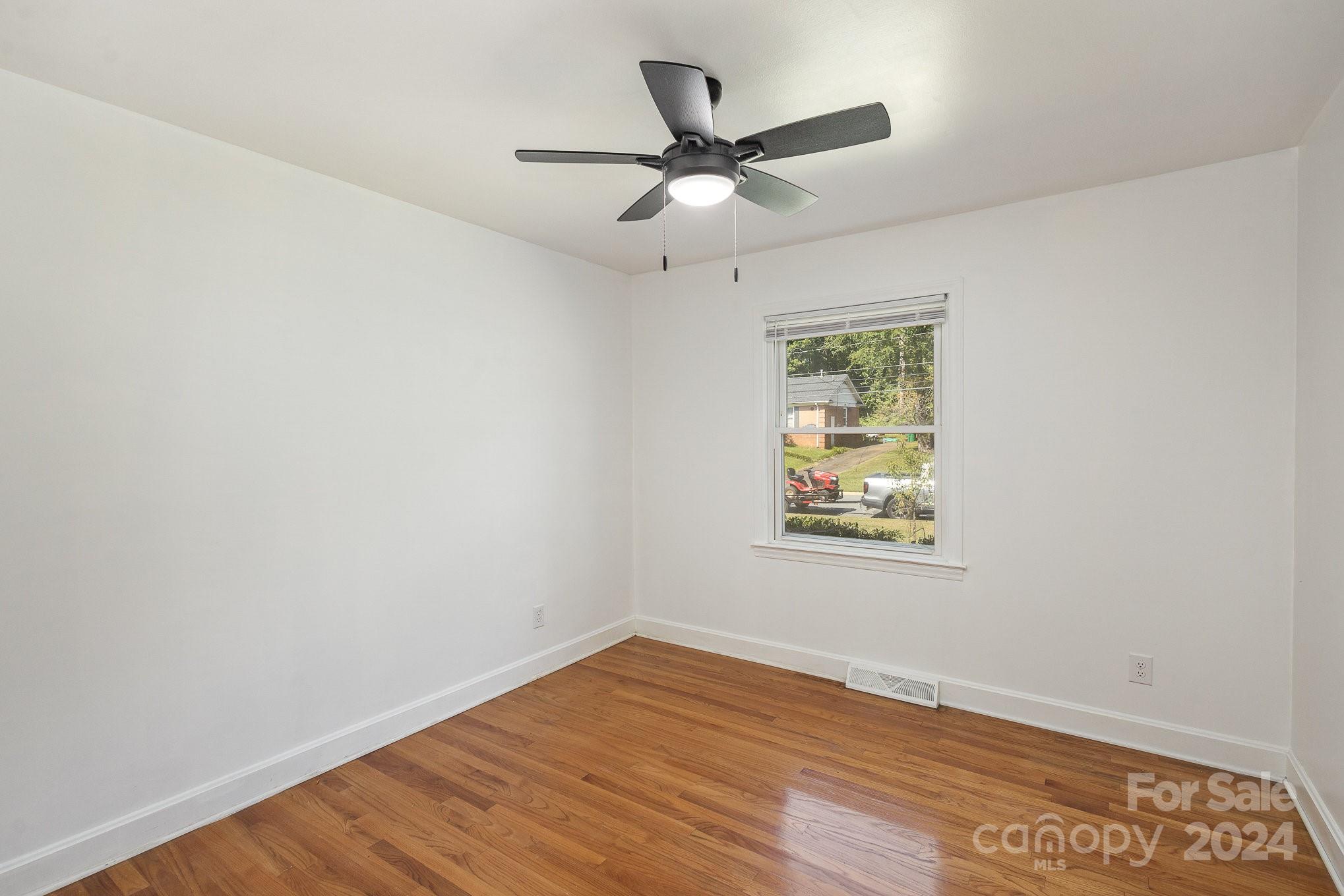 4431 Westridge Drive Charlotte, NC 28208 - Photo 16 of 24 an empty room with wooden floor window and ceiling fan