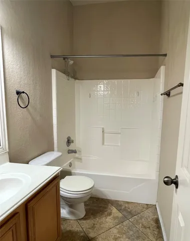 a bathroom with a granite countertop bathtub shower sink vanity and toilet