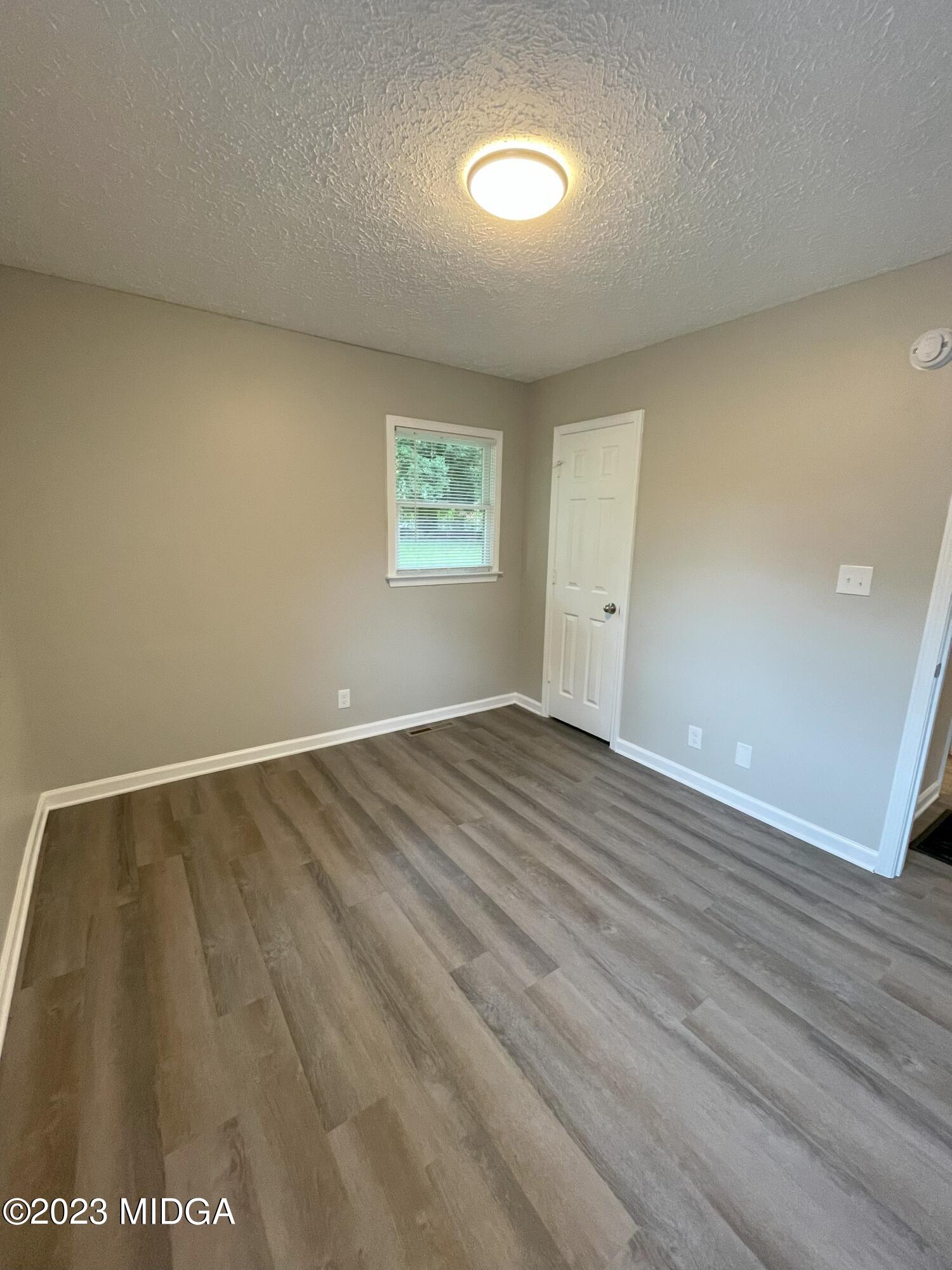 1437 Canterbury Road Macon, GA 31206 - Photo 13 of 18 an empty room with wooden floor and windows