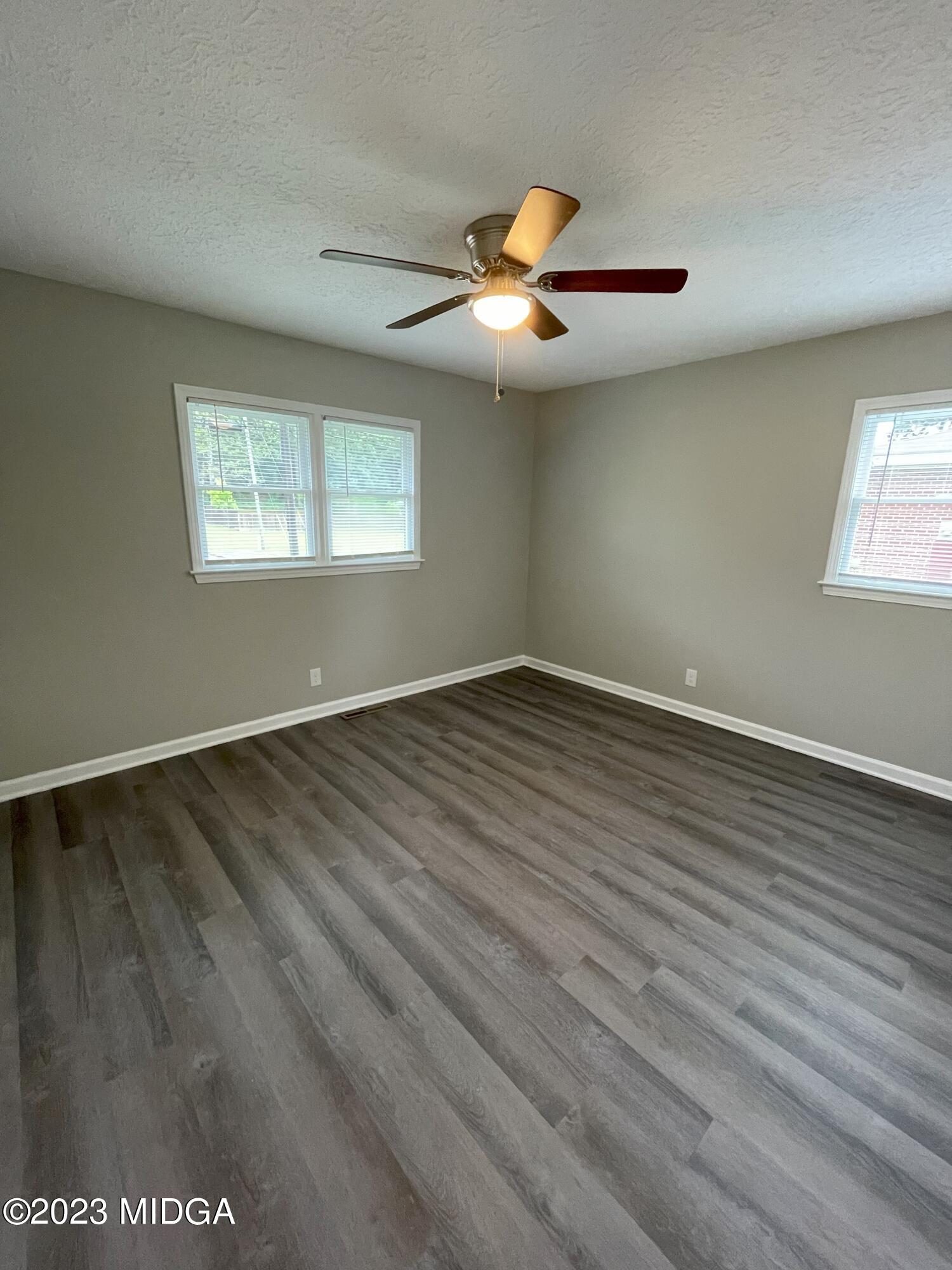 1437 Canterbury Road Macon, GA 31206 - Photo 14 of 18 an empty room with wooden floor chandelier fan and windows