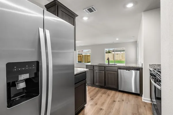 a kitchen with stainless steel appliances granite countertop a refrigerator a stove and a wooden floors