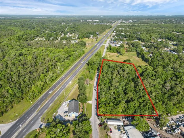 an aerial view of residential houses with outdoor space and trees