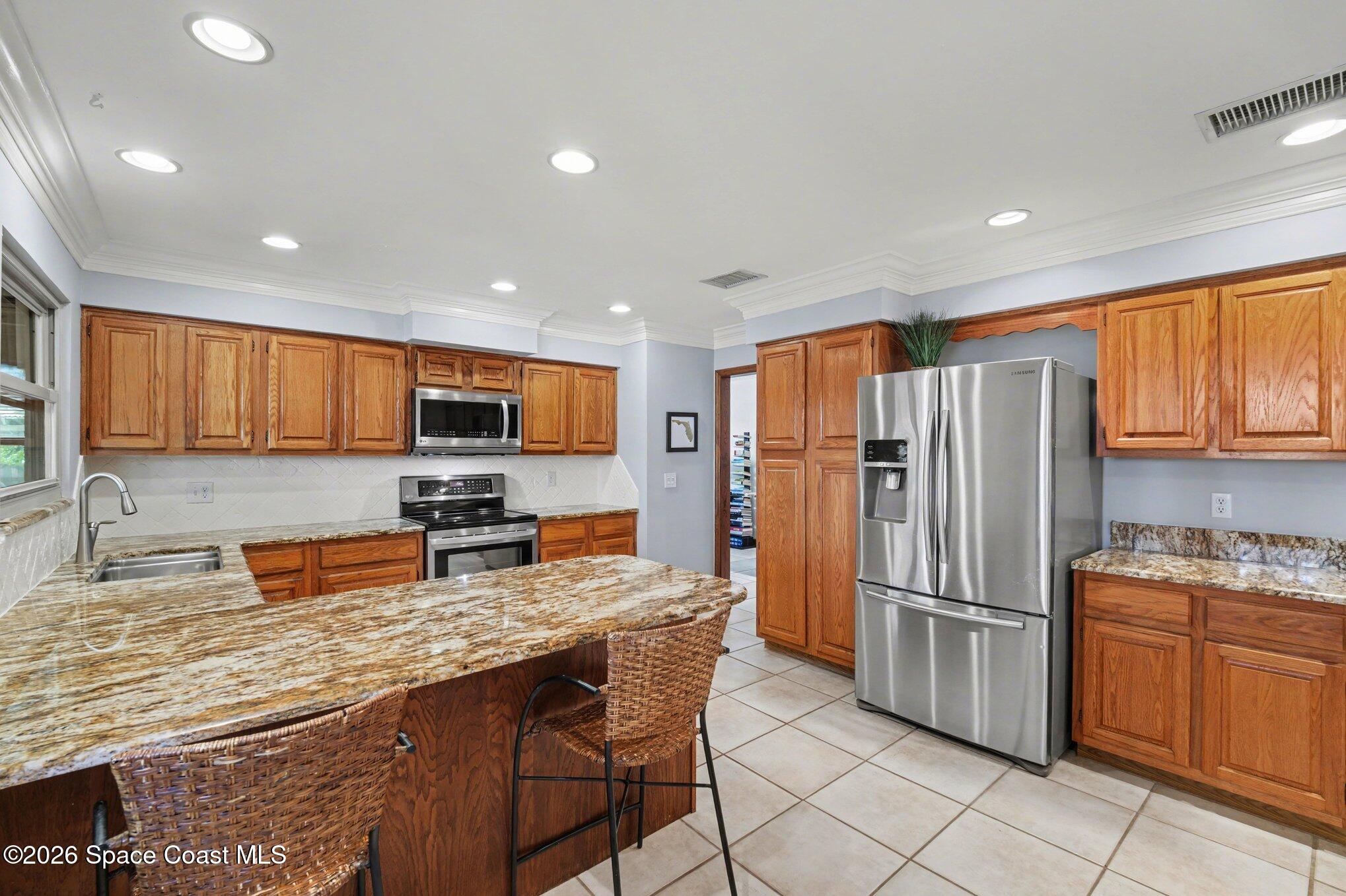 568 Rio Casa Drive North Indialantic, FL 32903 - Photo 8 of 45 a kitchen with stainless steel appliances granite countertop a refrigerator and a stove top oven