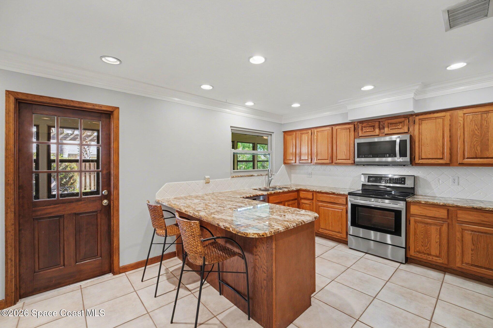 568 Rio Casa Drive North Indialantic, FL 32903 - Photo 9 of 45 a kitchen with stainless steel appliances granite countertop a stove a sink a microwave and a refrigerator