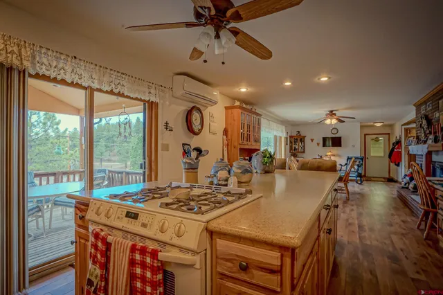 a kitchen with a stove a refrigerator a dining table and chairs with wooden floor