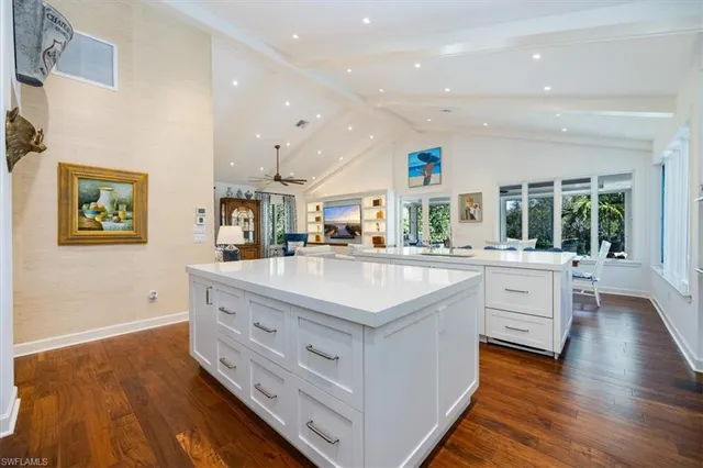 a large white kitchen with a large counter top space and stainless steel appliances