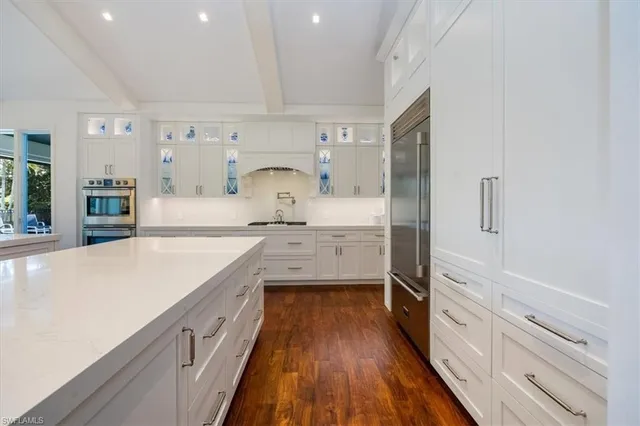 a large kitchen with a wooden floor and stainless steel appliances
