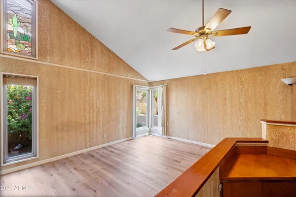 a view of empty room with wooden floor and fan