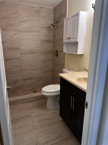 a bathroom with a granite countertop sink toilet and shower