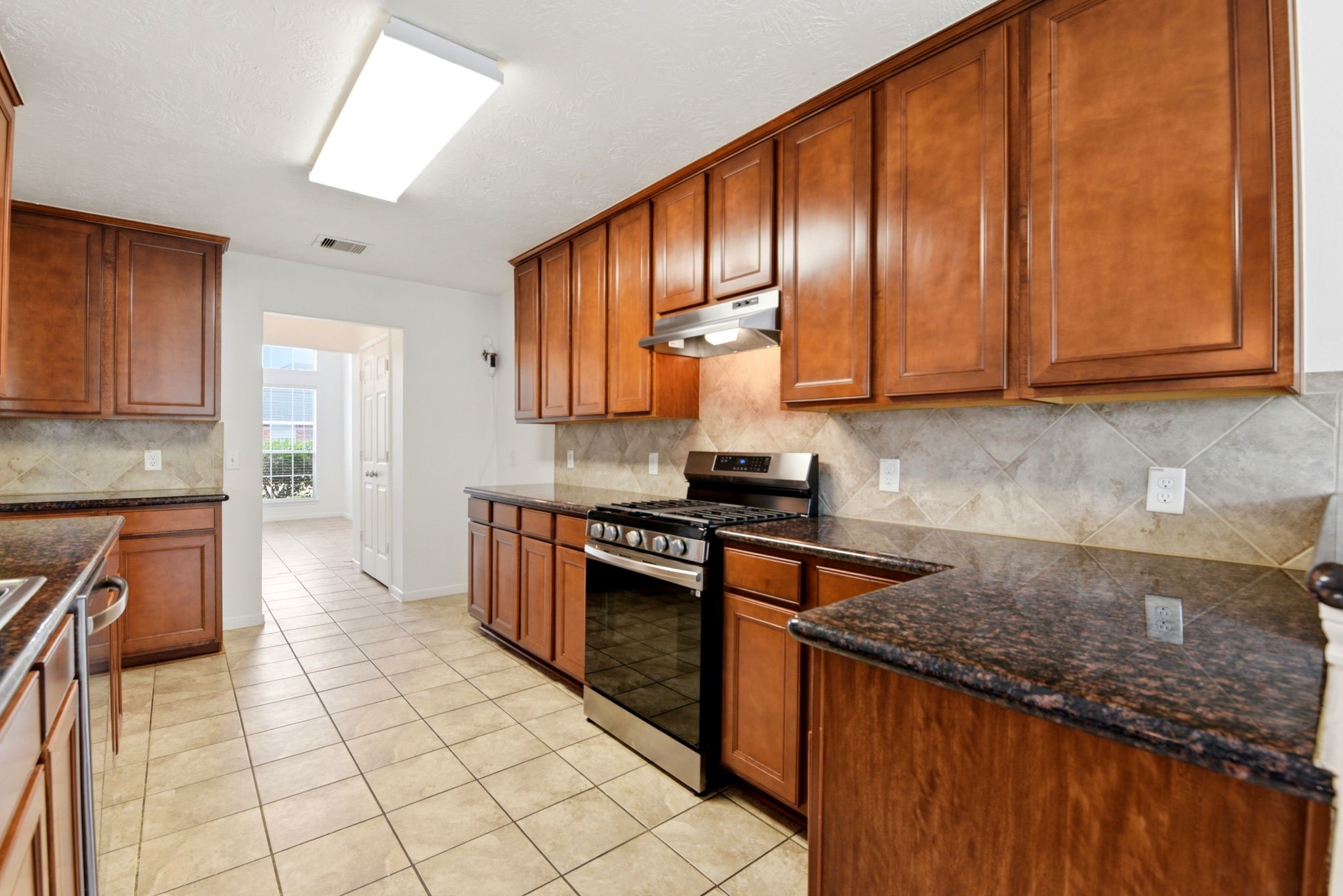 22102 Bridgestone Crossing Drive Spring, TX 77388 - Photo 10 of 38 a kitchen with stainless steel appliances granite countertop wooden cabinets a stove top oven a sink and dishwasher