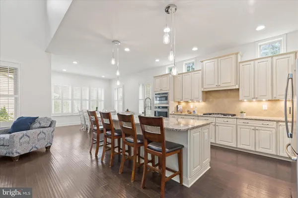 a kitchen with a dining table chairs refrigerator wooden floor and cabinets