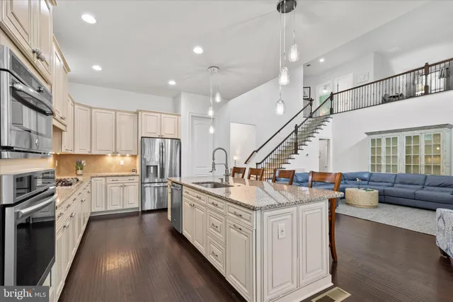 a large kitchen with kitchen island granite countertop lots of white cabinets appliances and furniture