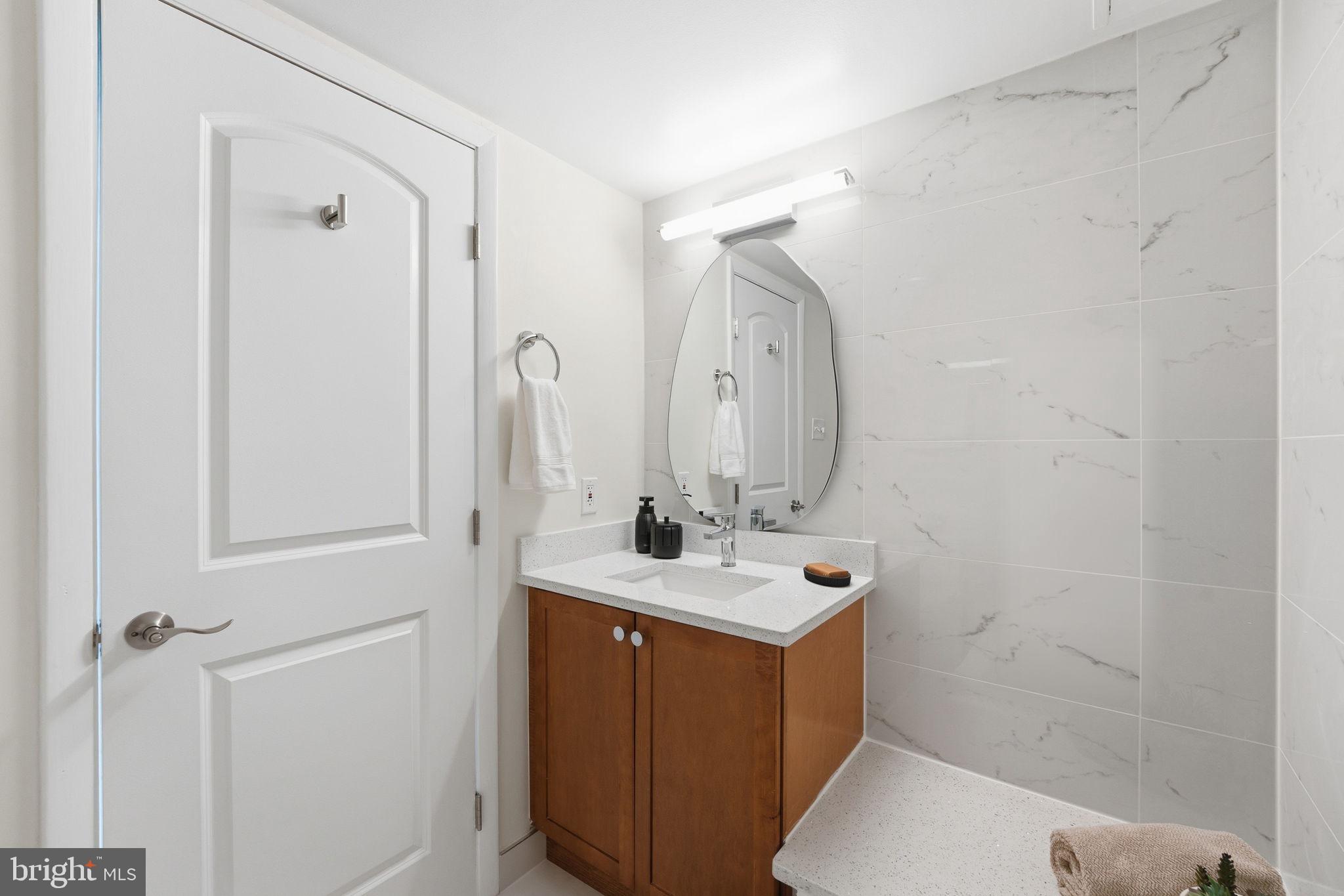 1245 13th Street Northwest, Unit 901 Washington, DC 20005 - Photo 32 of 38 a bathroom with a sink a mirror a vanity and a shower