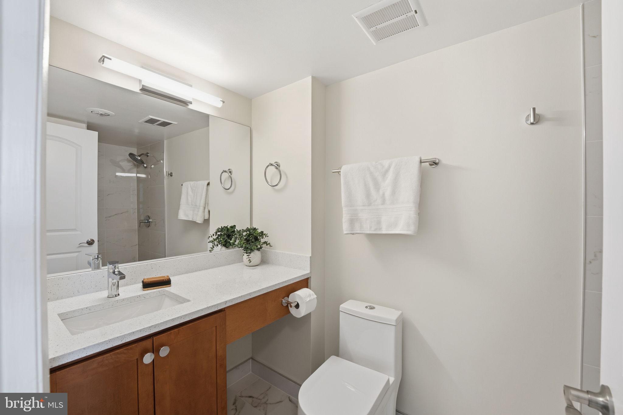1245 13th Street Northwest, Unit 901 Washington, DC 20005 - Photo 7 of 38 a bathroom with a granite countertop toilet sink and mirror