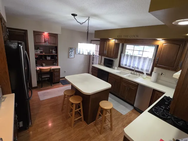 a kitchen with granite countertop a table chairs microwave and refrigerator