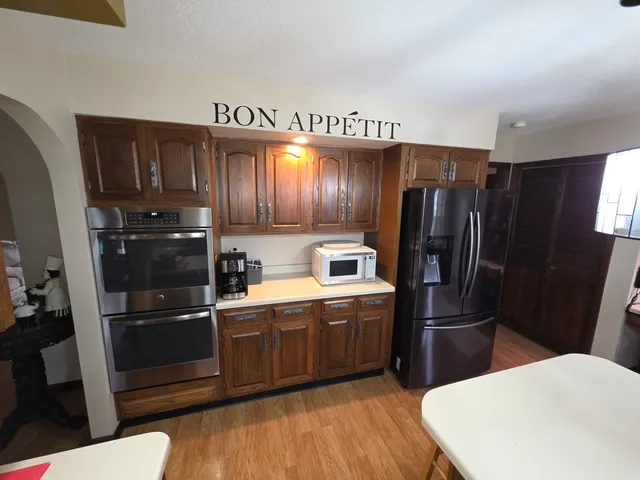 a kitchen with stainless steel appliances granite countertop a sink a stove a refrigerator a dining table and chairs with wooden floor