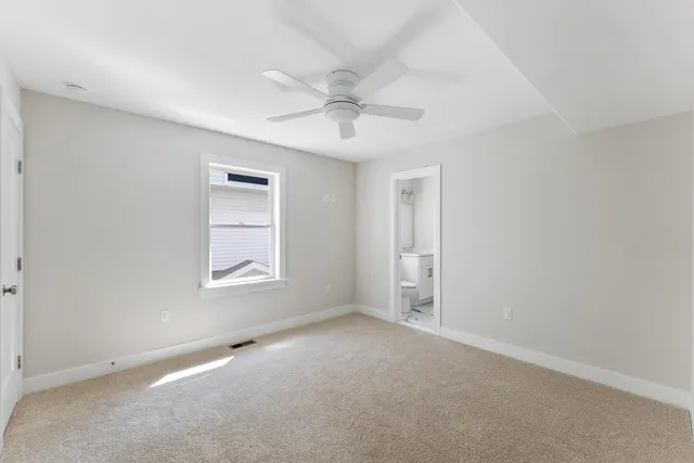 an empty room with windows and fan