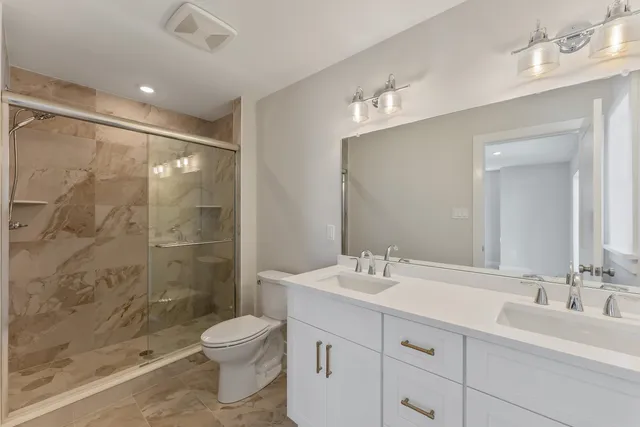 a bathroom with a double vanity sink toilet and shower