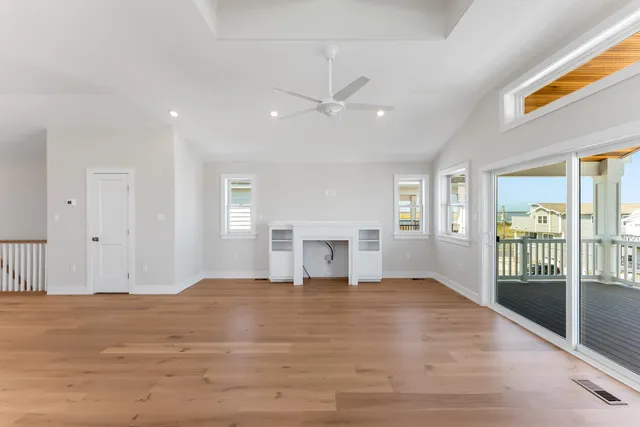 a view of an empty room with window and wooden floor