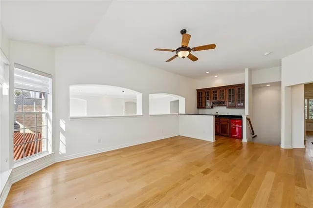 an empty room with a chandelier fan and windows