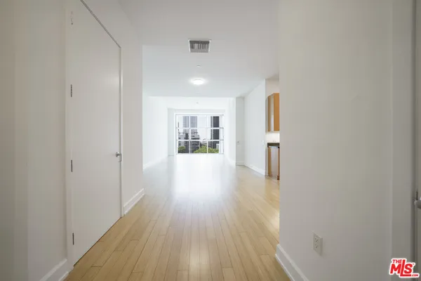 a view of a hallway with wooden floor and a refrigerator
