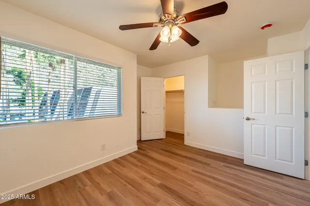 a view of empty room with wooden floor and fan