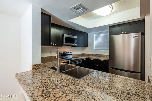 a kitchen with granite countertop a refrigerator and a stove top oven