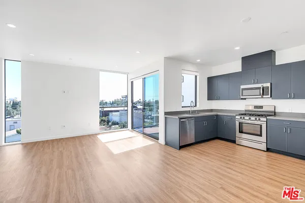 a large kitchen with a wooden floor and large stainless steel appliances