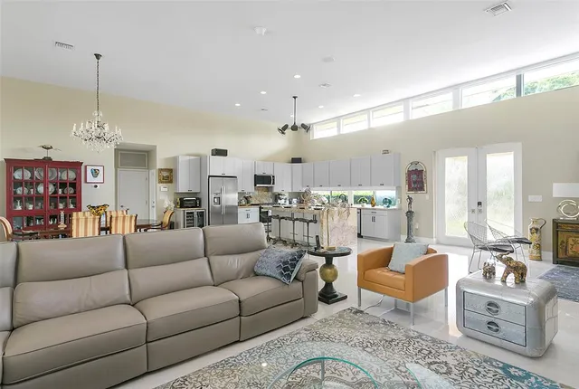 a living room with furniture kitchen view and a chandelier