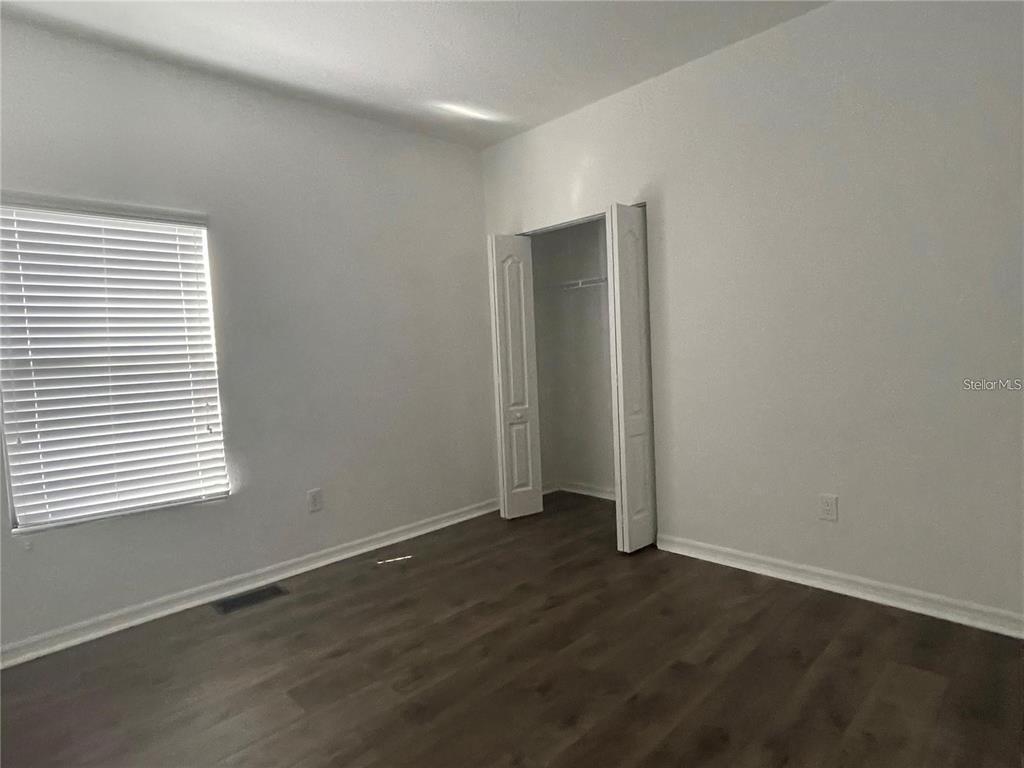 3731 Seneca Club Loop, Unit B Orlando, FL 32808 - Photo 17 of 32 an empty room with wooden floor and windows