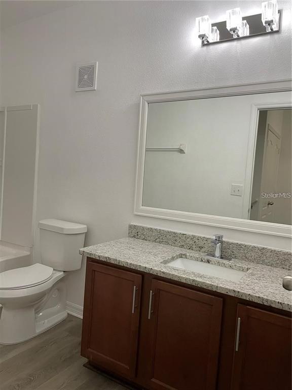 3731 Seneca Club Loop, Unit B Orlando, FL 32808 - Photo 19 of 32 a bathroom with a granite countertop sink a toilet and a mirror
