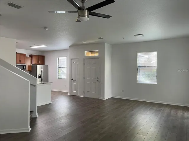 an empty room with wooden floor cabinet and windows