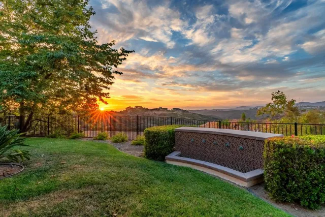 a view of a white house with a yard and table and chairs under an umbrella