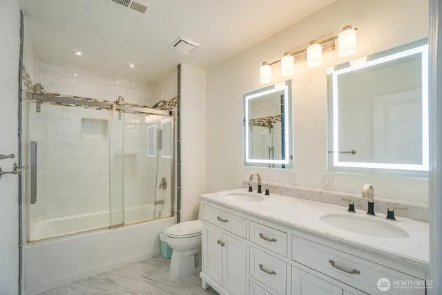 a bathroom with a double vanity sink toilet mirror and shower