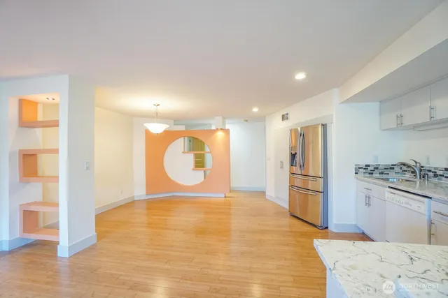 a view of an empty room with a window and wooden floor
