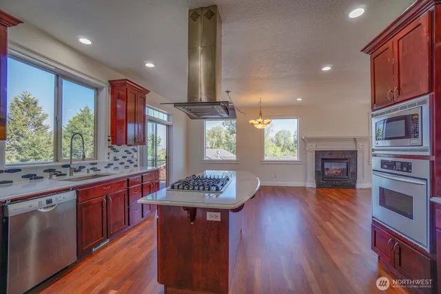 a kitchen with stainless steel appliances granite countertop a stove and a wooden floors