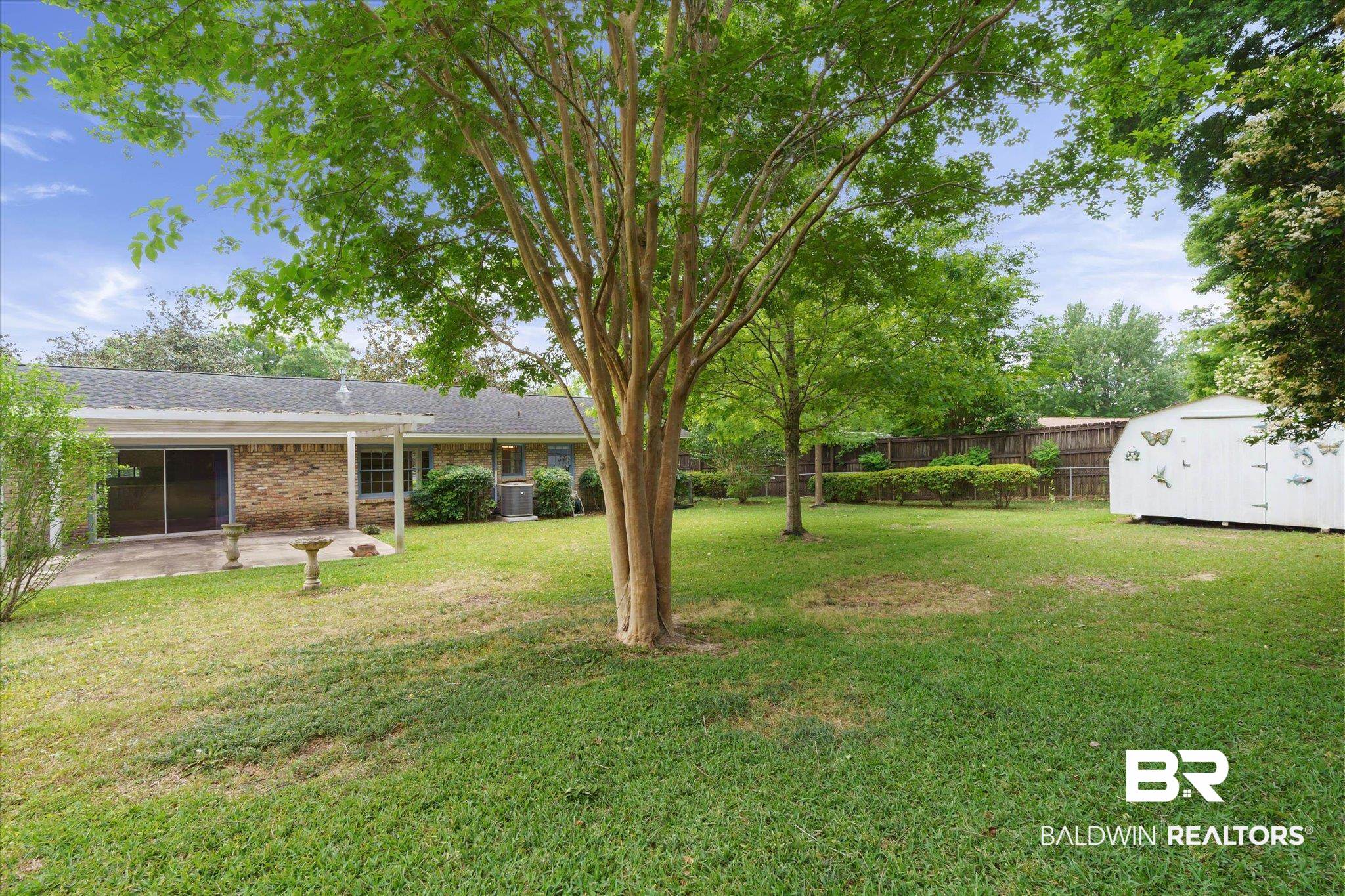 1182 Ginger Drive Mobile, AL 36693 - Photo 33 of 37 Expansive backyard featuring mature trees, a manicured lawn, a covered patio with direct access to the interior, and a white storage shed