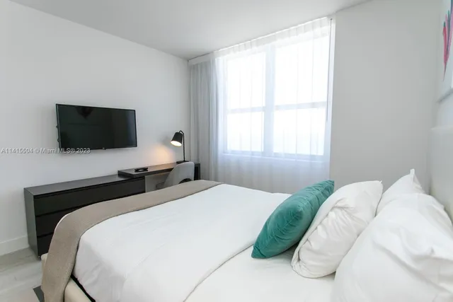 a bedroom with a bed tv and window