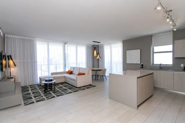 a living room with furniture a large window and a chandelier