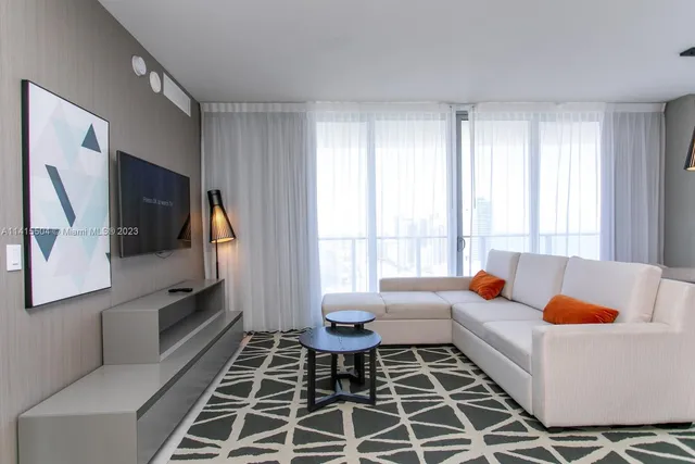 a living room with furniture a flat screen tv and a window