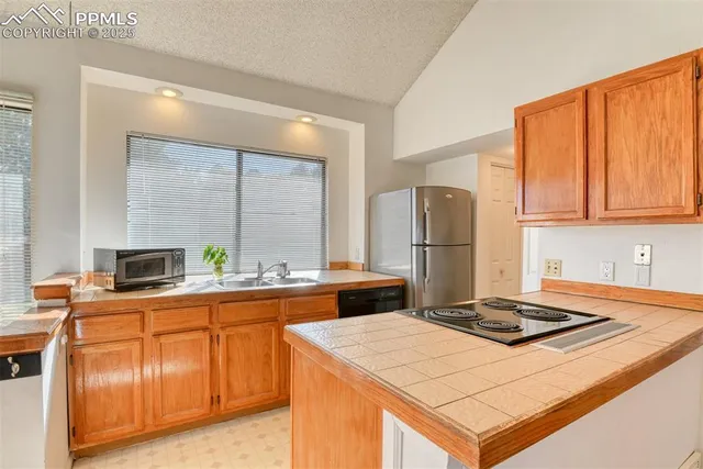 a kitchen with kitchen island granite countertop a sink stove and refrigerator